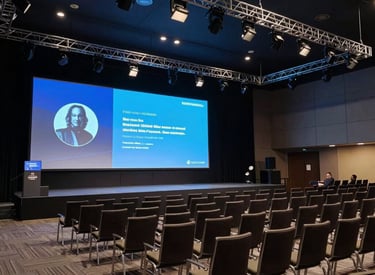 A professional high-tech conference hall in South America with rows of modern chairs, a large projection screen showing Steel Blue graphics, and a sophisticated lighting rig overhead, professional atmosphere.