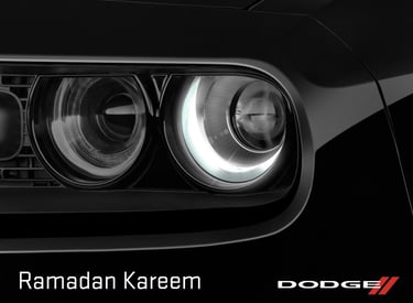 Close-up of a black Dodge Challenger headlight with Ramadan Kareem text and brand logo.