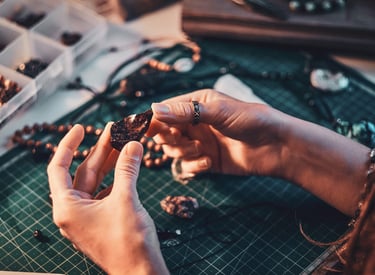 Artesana seleccionando piedra natural en bruto para crear joyería artesanal hecha a mano.