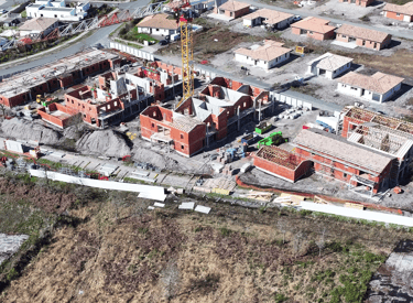 Vue aérienne d'un chantier résidentiel avec maisons en briques et une grue à tour jaune.