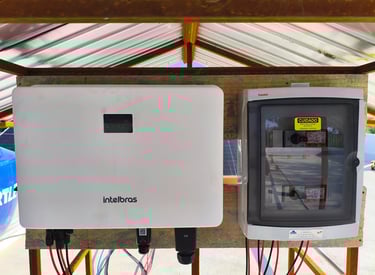 White Intelbras solar inverter and electrical string box mounted for a PV energy system.