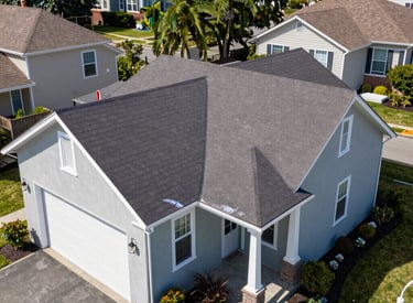 A cozy house with a freshly installed shingle roof under a bright blue sky.