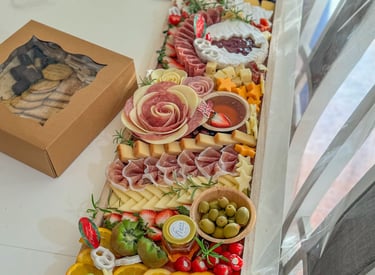 abla de charcutería navideña festiva con rosas de salami, brie, aceitunas y fruta fresca.