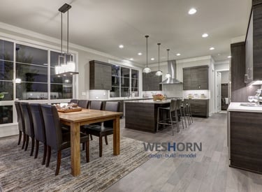 Modern open concept kitchen and dining room featuring dark wood cabinets and a rustic oak table.