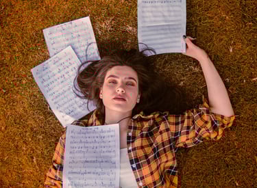 Dans ce projet photo Denis Studio, une jeune artiste musicienne repose sur l’herbe, regard caméra