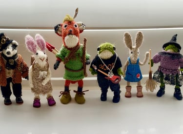 A collection of little knitted woodland animal ornaments in clothes, badgers, foxes, bunny rabbits a