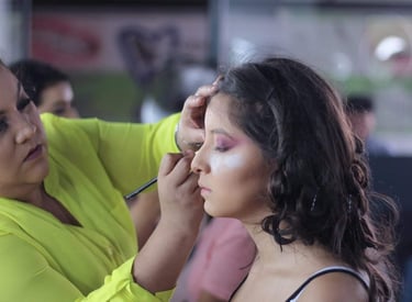 Maquilladora profesional aplica sombra de ojos morada a una mujer joven para un evento especial.