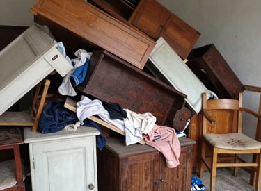 Stacked tires, a mattress leaning against a wall, and containers of chemicals with warning labels.