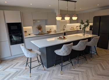 white kitchen with black refridgerator, comfy white stools and flowers