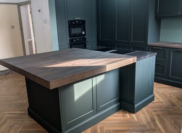 elegant wooden kitchn countertop with a set of dark green cupboards
