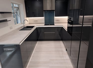 reflective black kitchen cuboards with a white countertop