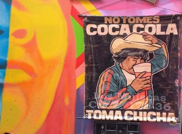 Colorful street art and posters on a wall in La Candelaria, Bogota, promoting traditional Chicha.