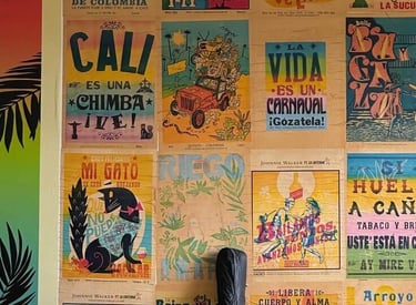 Colorful gallery wall featuring vintage Colombian salsa posters and art prints above a sofa with a guitar case.