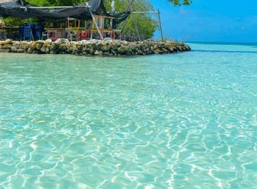 Crystal clear turquoise water ripples in front of a tropical beach bar on a sunny island.