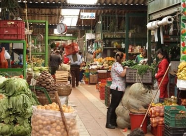 Bustling indoor farmers market featuring fresh local produce, leafy greens, and vendors selling vegetables.