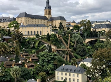Panoramic view of Luxembourg City's historic Grund district with Neumünster Abbey and lush valley gardens.