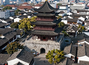 Aerial view of the historic Drum Tower in Ningbo, China, surrounded by traditional architecture and a modern city skyline.