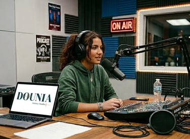 Young woman recording a podcast in a professional radio studio with a microphone, laptop, and mixer.