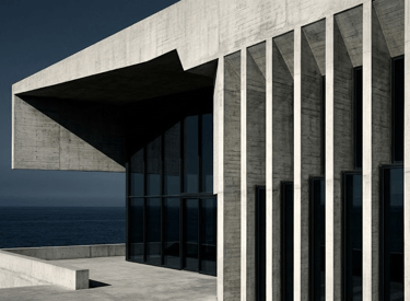 Modern brutalist concrete building with vertical pillars and glass walls overlooking the ocean.
