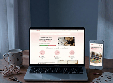 A laptop and smartphone displaying a responsive handmade crafts website on a wooden desk with a cherry blossom theme.