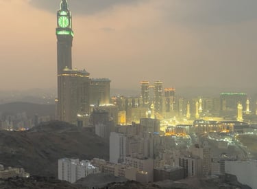 Makkah Royal Clock Tower and Great Mosque of Mecca at sunset from a rocky overlook.