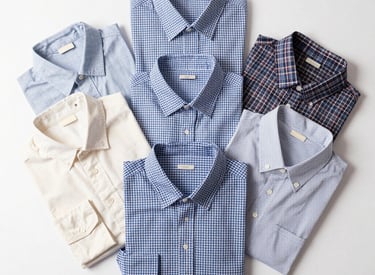 Stacks of neatly folded premium men's shirts ready for shipment in a clean warehouse.