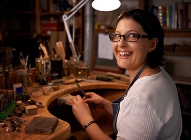 Mujer en taller de joyería tallando un anillo artesanalmente