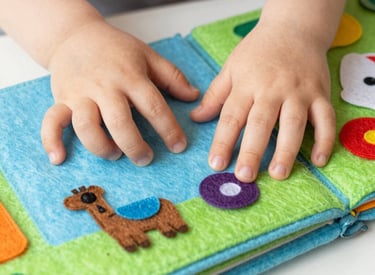 Brightly stitched bibs hanging on a clothesline under sunlight.