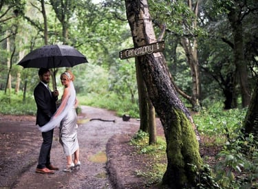 bride and groom in woodland setting holding an umbrella