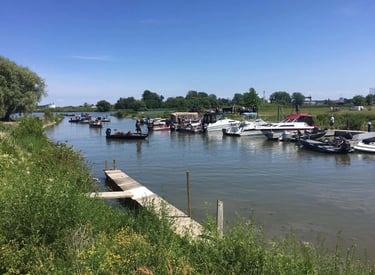 Various motorboats and fishing boats docked at a marina on a sunny day with a wooden pier.