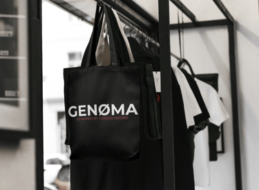 bolsa ecologica negra con el logotipo de genoma y estampada por genoma colgada en el perchero,