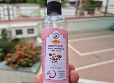 a person holding a bottle of berryfruit hand cream