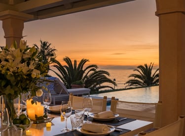 Candlelit dining setting at sunset beside infinity pool and ocean