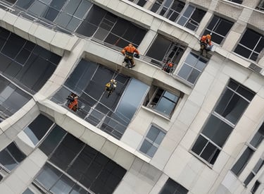 A high-rise building with a modern architectural design features a series of glass panes and sharp geometric shapes. The structure appears to have multiple protruding sections with reflective surfaces, creating a pattern of lines and angles.