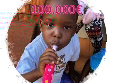 Kind aus Uganda mit Tröte im Mund und der Zahl 100.000