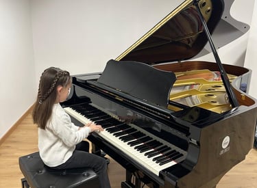 a young girl playing a baby grand piano in a music school