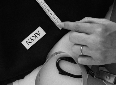 Designer Amy Powney adjusting garments on rail inside London studio