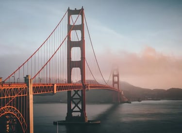 Golden Gate Bridge in San Francisco shrouded in morning fog during a golden hour sunrise.