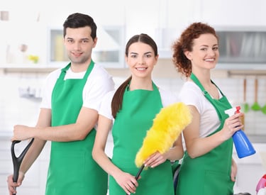 a group of people in green aprons holding cleaning supplies