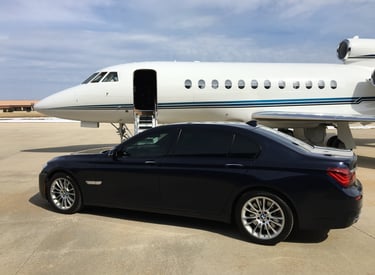 BMW 7 Series parked next to a Falcon 900EX on a ramp