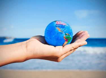 globus in offern hand mit strand im hintergrund bei richtig auswandern dexit online