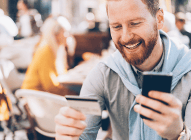 mann testet mobil banking zahlungssysteme  mit handy und kreditkarte in hand