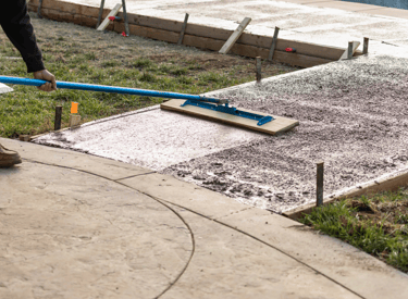 a man is using a blue broom to clean the concrete