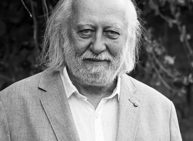 Black and white portrait of an elderly man in a blazer, possibly László Krasznahorkai, with his face