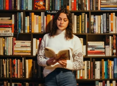 a woman standing in front of a bookcase with books on it