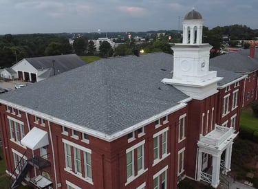 a large red brick building with a clock tower new roof