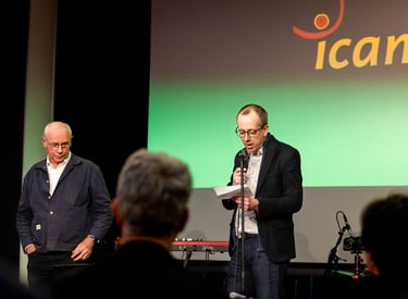 Un homme en veste noire un micro à la main