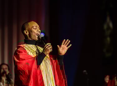 Un chanteur de gospel en toge dorée et rouge sur scène