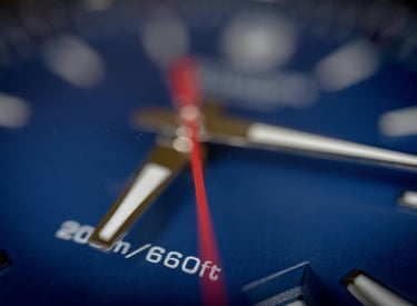 a close up of a blue watch face with a red line on the face of