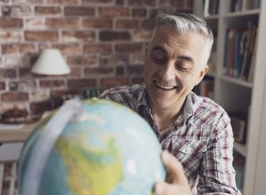 Homem sorridente segurando globo terrestre, representando expatriados e mobilidade global.